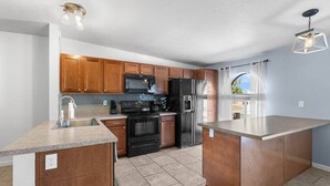 A modern kitchen with granite countertops, stainless steel appliances, and wooden cabinets.