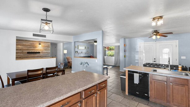 A modern kitchen with granite countertops, wooden cabinets, a built-in oven, and a ceiling fan.