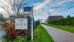 Een landweg met een bordje 'Rue D'Amontot' en een decoratief bord met uilen.