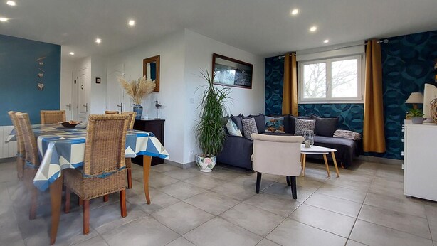 Een moderne woonkamer met een eethoek, met een bank, een salontafel en een eettafel met stoelen.
