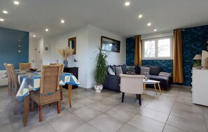 A modern living room with a dining area, featuring a sofa, a coffee table, and a dining table with chairs. - Lovely home in Pretot-Vicquemare (Pretot-Vicquemare)