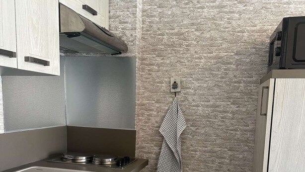 A compact kitchen with a modern design, featuring a stainless steel sink, wooden cabinets, and a stone-textured backsplash. - A practical one-bedroom flat with parking, close to the station and the beach (ARCACHON)