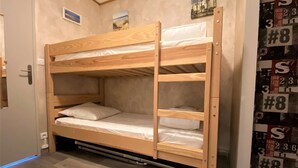 A bunk bed in a room with a door, a wall with numbered stickers, and a small picture above the bed. - A practical one-bedroom flat with parking, close to the station and the beach (ARCACHON)