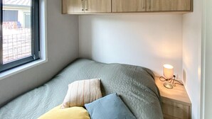 A small, cozy bedroom with a bed, pillows, a bedside lamp, and a window. - 3 bedroom lovely (sta)caravan in Grou (Grou)