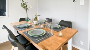 A dining table set with plates, glasses, and a bottle, surrounded by chairs. - 3 bedroom lovely (sta)caravan in Grou (Grou)
