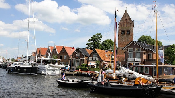 A harbor with boats docked, a church with a tower, and traditional houses with red roofs. - 3 bedroom lovely (sta)caravan in Grou (Grou)