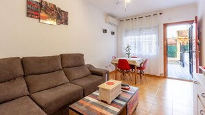 Ein Wohnzimmer mit braunem Sofa, einem Holztisch und einem Essbereich mit Tisch und Stühlen.