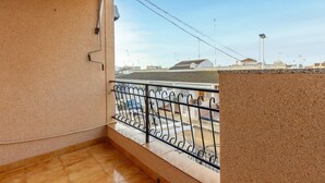Ein Balkon mit Metallgeländer, Blick auf eine Straße mit Autos und Gebäuden im Hintergrund.