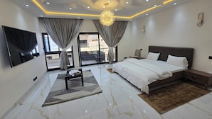 A modern bedroom with a large bed, a flat-screen TV, and a ceiling with recessed lighting. - Villa Harmony at Ngaparou in the Thiès region (Saly)