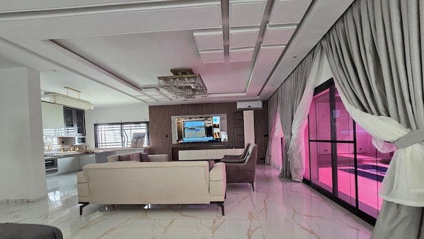 A modern living room with a large TV, comfortable seating, and a view of the outside. - Villa Harmony at Ngaparou in the Thiès region (Saly)