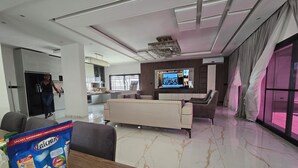 A modern living room with a sofa, a TV, and a dining area with a table and a bag of Laicran bread. - Villa Harmony at Ngaparou in the Thiès region (Saly)