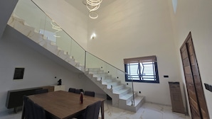 A modern interior with a marble staircase, a dining area, and a large window with blinds. - Villa Harmony at Ngaparou in the Thiès region (Saly)