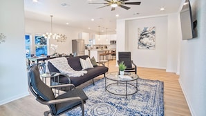 A modern living room with a sofa, armchairs, a coffee table, and a ceiling fan. - Urban Delight 4br/3ba Near City Center (San Antonio)