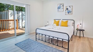 A bedroom with a bed, a small side table, and a view of the outside. - Urban Delight 4br/3ba Near City Center (San Antonio)