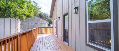 A wooden deck leading to a building with a large window and a door.