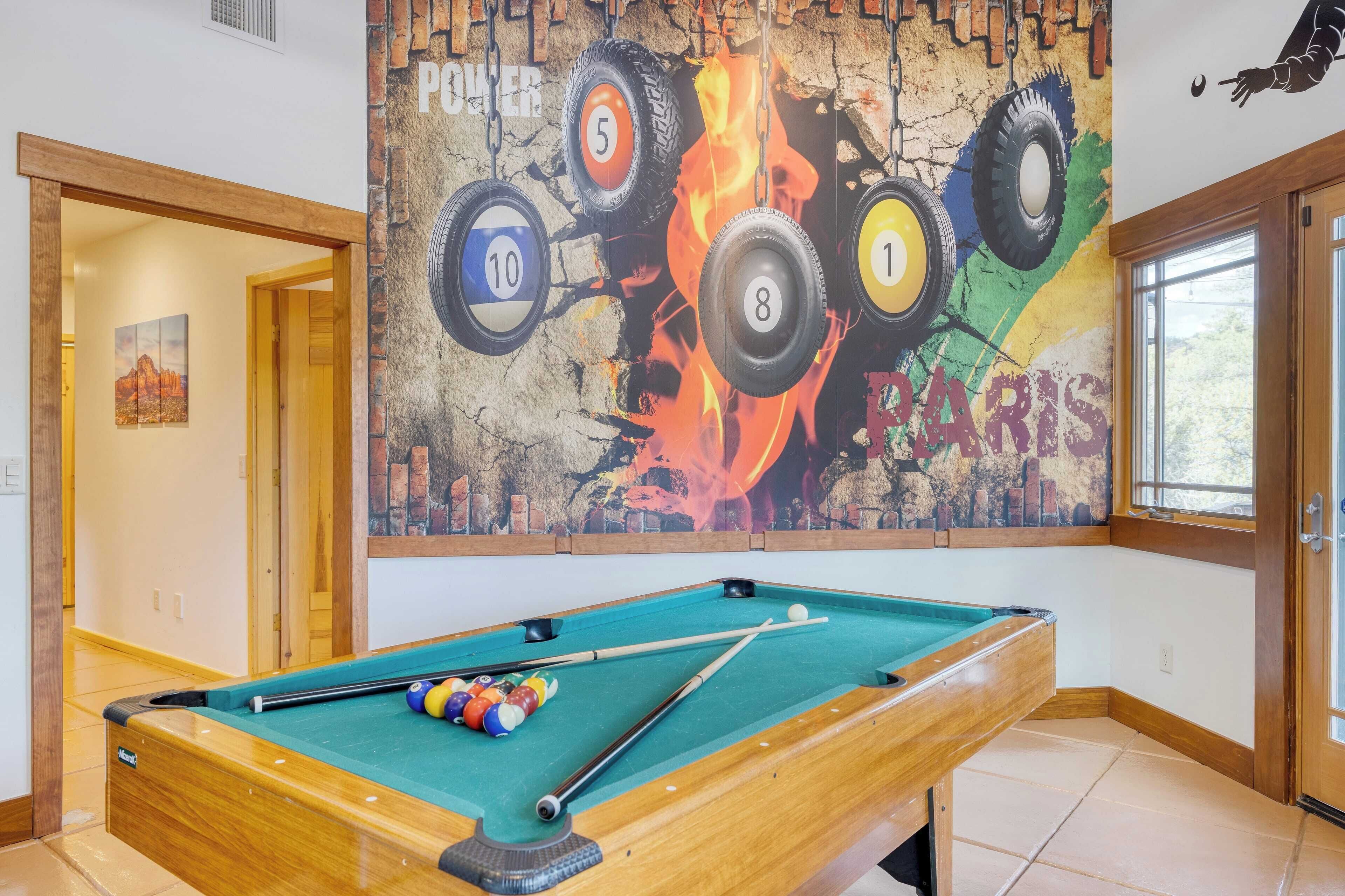 A pool table in a room with a mural of tires and the word "PARIS" on the wall.