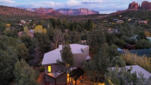 A modern house with a balcony, surrounded by dense trees and mountains in the background. - Pool Table + Hot Tub + Scenic Views Cathedral View by Avantstay (Sedona)