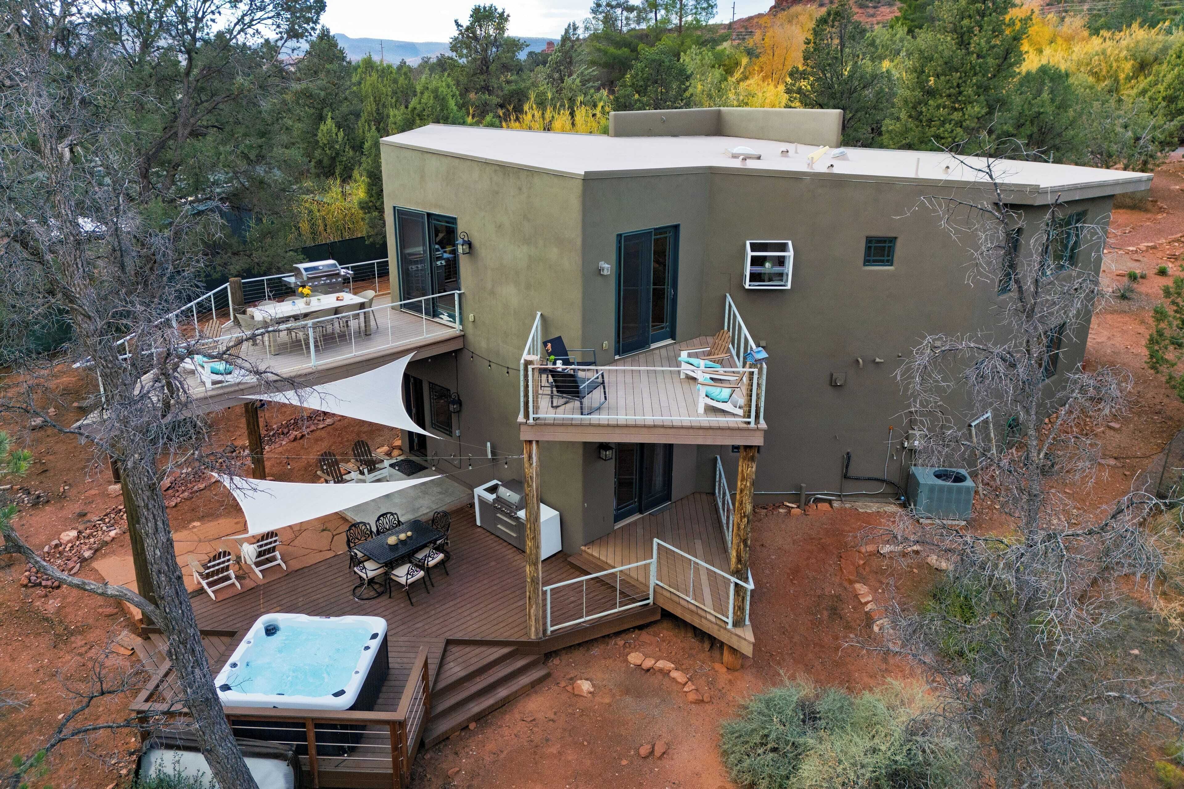 A modern two-story house with a deck, outdoor seating, and a hot tub.