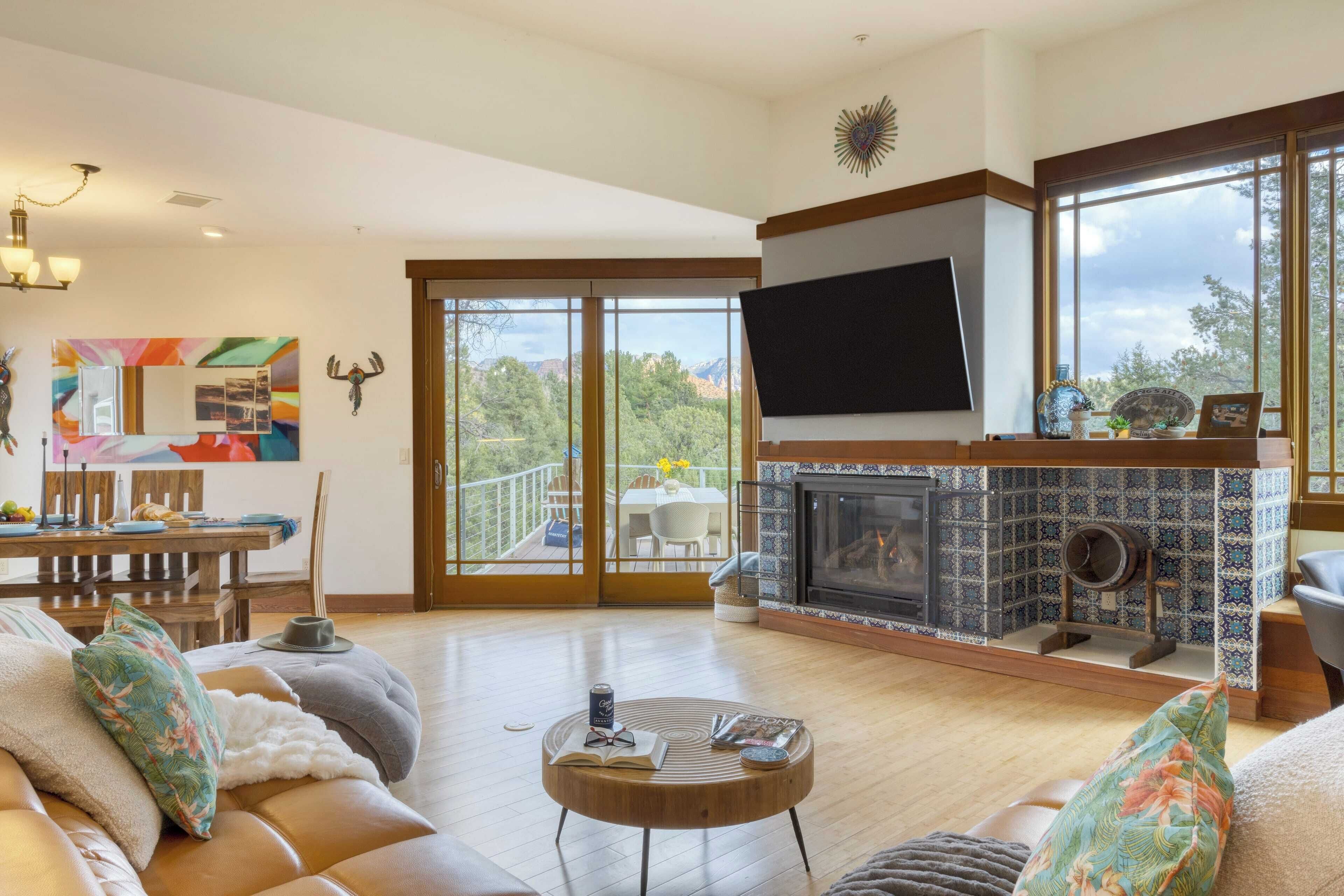 A spacious living room with a fireplace, a large TV, and a balcony with a dining area.