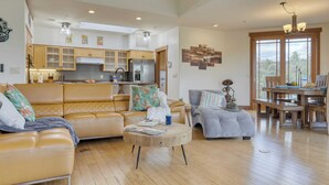 A spacious living room with a large sofa, a round coffee table, and a dining area with wooden furniture. - Pool Table + Hot Tub + Scenic Views Cathedral View by Avantstay (Sedona)