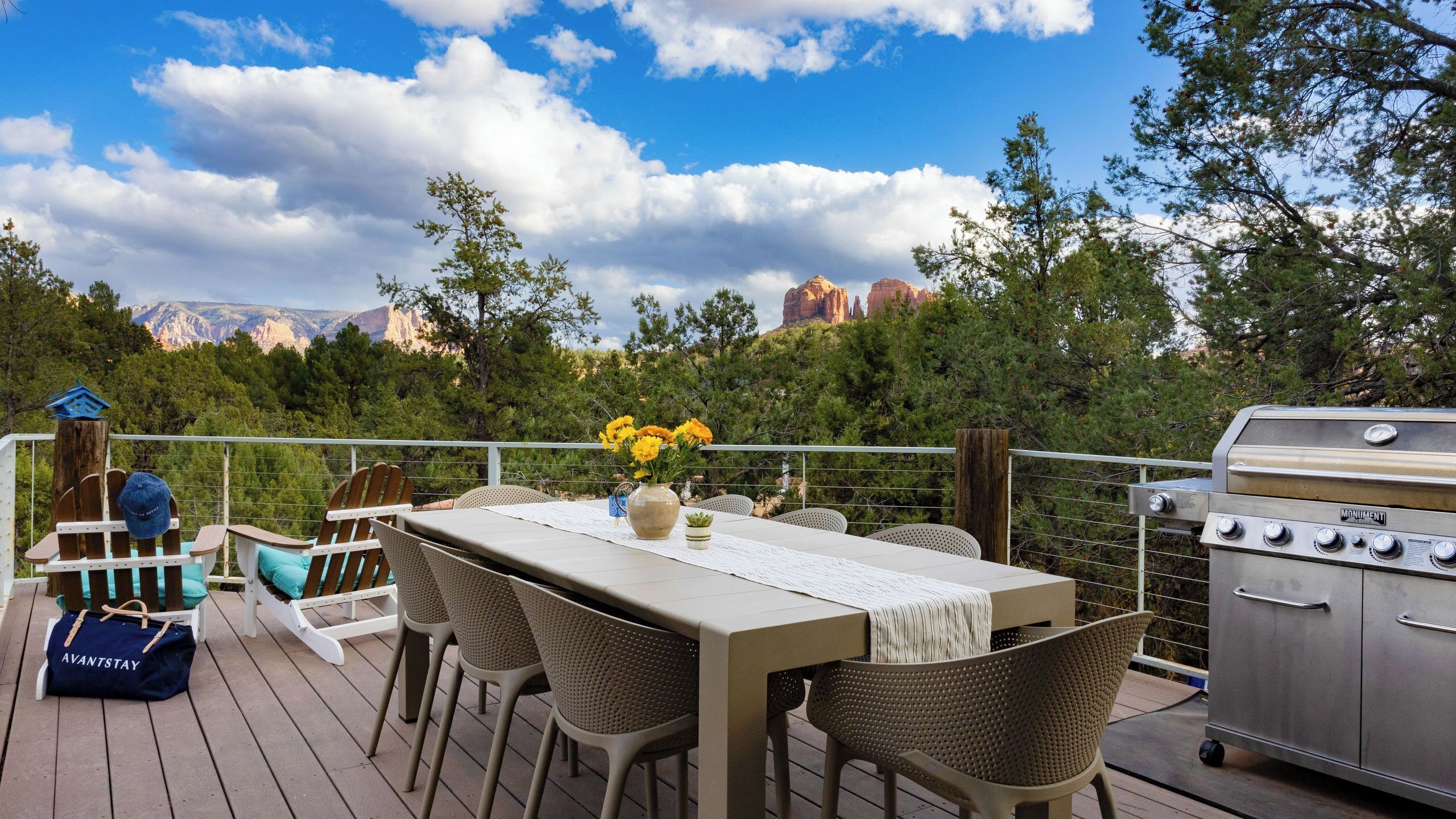 Une terrasse avec une table, des chaises, un barbecue et une vue sur les montagnes.