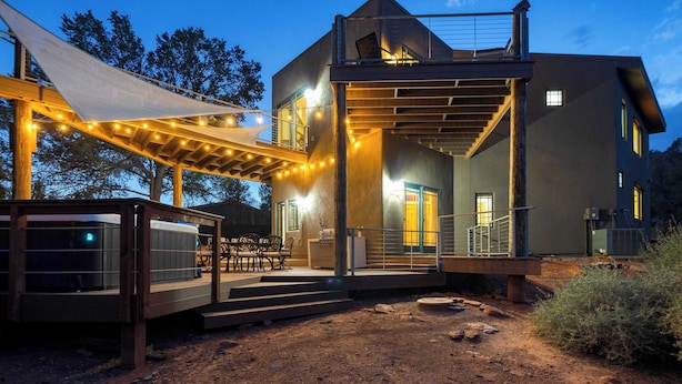 A modern two-story house with a covered patio, outdoor seating, and a dirt ground. - Pool Table + Hot Tub + Scenic Views Cathedral View by Avantstay (Sedona)