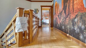 A wooden staircase with a 'Out of Office' sign, a mural of a desert landscape, and a hallway leading to another room. - Pool Table + Hot Tub + Scenic Views Cathedral View by Avantstay (Sedona)