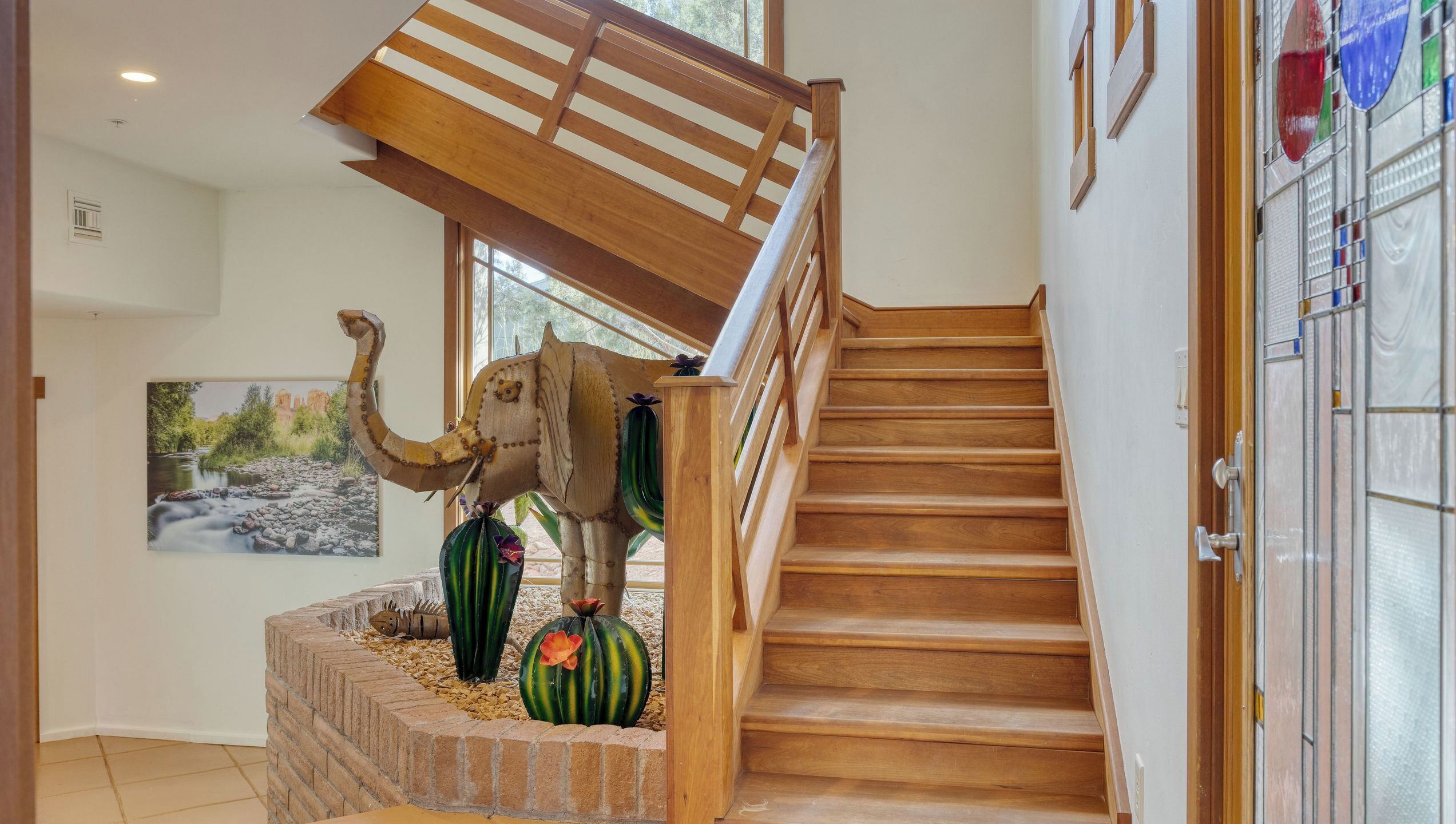 Un escalier en bois avec une rampe en bois et un tableau accroché au mur.