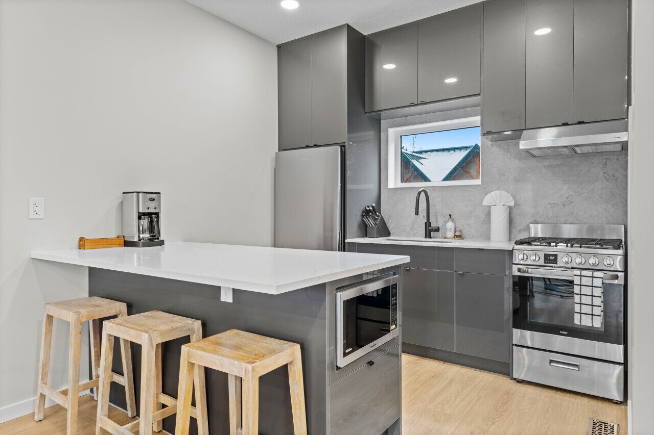 Una cocina moderna con una isla central, electrodomésticos de acero inoxidable y taburetes de madera.