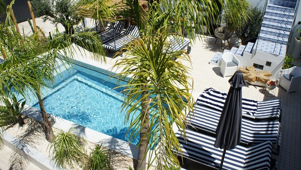 A rooftop pool area with lounge chairs and umbrellas, surrounded by palm trees and a staircase. - Walking distance to several beaches, Ferragudo village, supermarkets and Portimão. (Ferragudo)