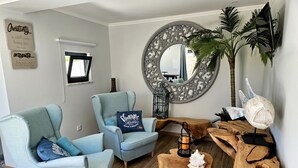 A living room with two light blue armchairs, a wooden coffee table, a round mirror, and a decorative wooden piece. - Walking distance to several beaches, Ferragudo village, supermarkets and Portimão. (Ferragudo)