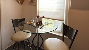 A dining area with a glass table and black chairs, a window with blinds, and a wooden ceiling. - Charming Waterfront Loft + NearShops+Scenic (Quinte West)