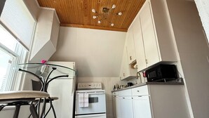 A compact kitchen with white cabinets, a white stove, and a black microwave. - Charming Waterfront Loft + NearShops+Scenic (Quinte West)