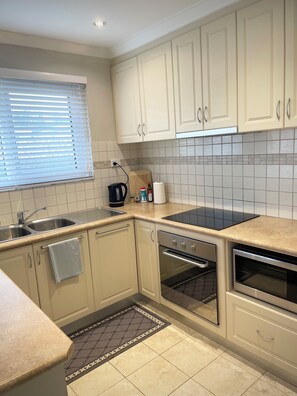 A kitchen with white cabinets, a black stove, a sink, and a window with blinds. - Private and Secure, 3 bed 1.5 bath  (Kardinya)