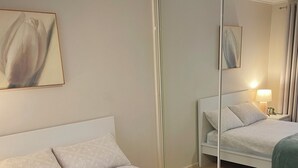 Une chambre d’hôtel avec un grand lit, une table de chevet avec une lampe et un miroir au mur.