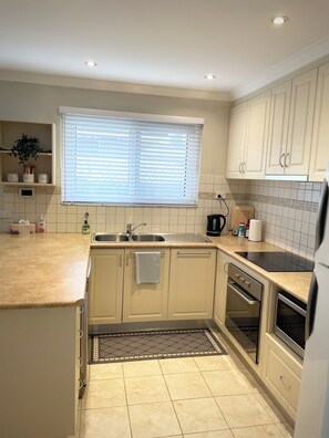 A kitchen with a window, sink, stove, oven, and cabinets. - Private and Secure, 3 bed 1.5 bath (Kardinya)