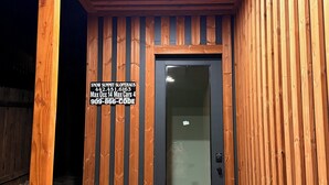 A wooden exterior with a dark door and a sign indicating a maximum occupancy of 14 cars and 4 people. - Brand New Gorgeous home in fantastic Big Bear Lake right on Snow summit Resort! (Big Bear Lake)