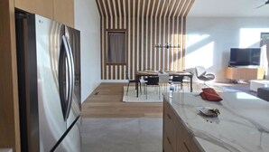 A modern kitchen with a built-in LG refrigerator, wooden ceiling beams, a dining area with a table and chairs, and a marble countertop. - Brand New Gorgeous home in fantastic Big Bear Lake right on Snow summit Resort! (Big Bear Lake)