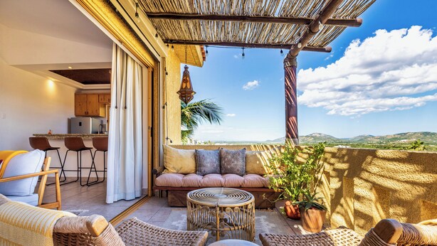 A cozy outdoor seating area with wicker furniture, a small round table, and a view of the landscape. - 3 Bd Penthouse in the heart of San Jose Del Cabo (San Jose del Cabo)