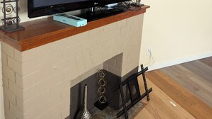A flat-screen TV on a wooden mantel above a brick fireplace, with a "NO SIGNAL" message on the screen.