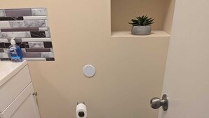 A small bathroom with a toilet, a trash can, and a toilet paper holder.