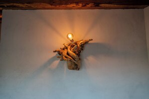 A wall-mounted light fixture with a bulb, set against a plain wall. - Il Capriccio del Papa (Genga)