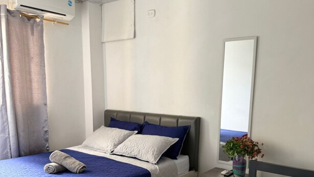 Quarto de hotel com duas camas, uma mesinha de cabeceira, um espelho, ar-condicionado e uma janela com vista.