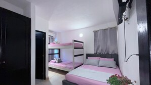 Um quarto com beliches, uma mesa de cabeceira com uma planta e uma janela com cortinas.