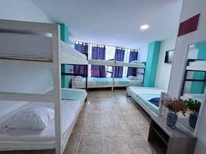 A dormitory room with bunk beds, a tiled floor, and a window with curtains. - Hotel Arena Mar (Santa Marta)