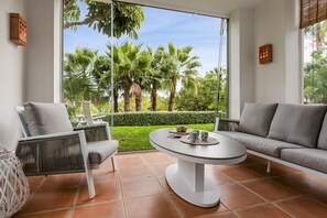 A modern living room with a round table, two sofas, and a view of a lush garden through large windows. - Casa Sereno | lagoon - pool - garden - view (Casares)