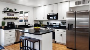 Una cocina moderna con gabinetes blancos, electrodomésticos de acero inoxidable y una isla central.