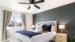 Un dormitorio con cama, mesita de noche y ventilador de techo.