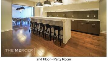 A modern kitchen with bar stools, pendant lighting, and a view to a dining area.