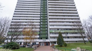 A high-rise building with multiple floors, featuring a central green section and a mix of white and green facades. - Park Śląski 18th Floor Apartment (Katowice)